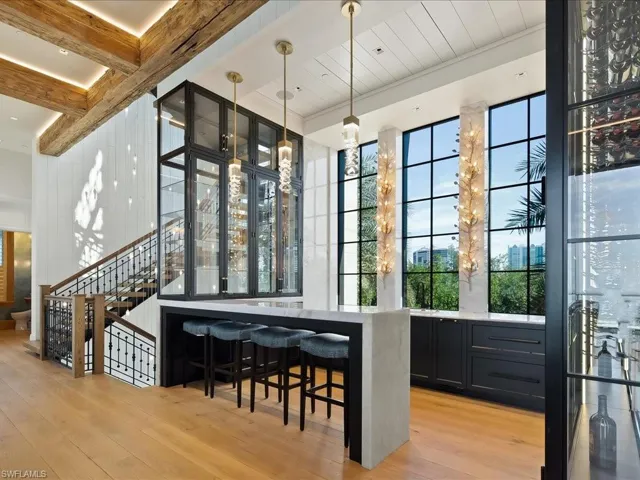 Bar area featuring pendant lighting, light stone countertops, stairs, light wood-style flooring, and beam ceiling