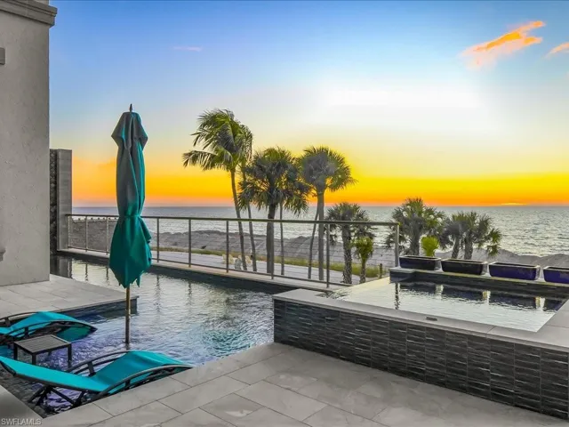 Pool at dusk featuring an infinity pool, a patio, and a water view