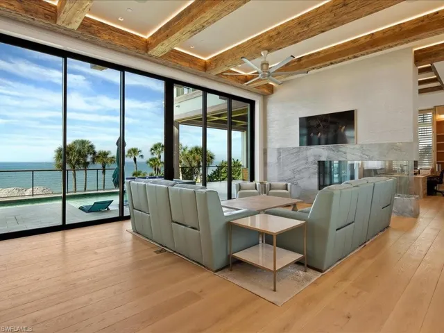 Living room with a water view, beam ceiling, light wood-type flooring, and ceiling fan