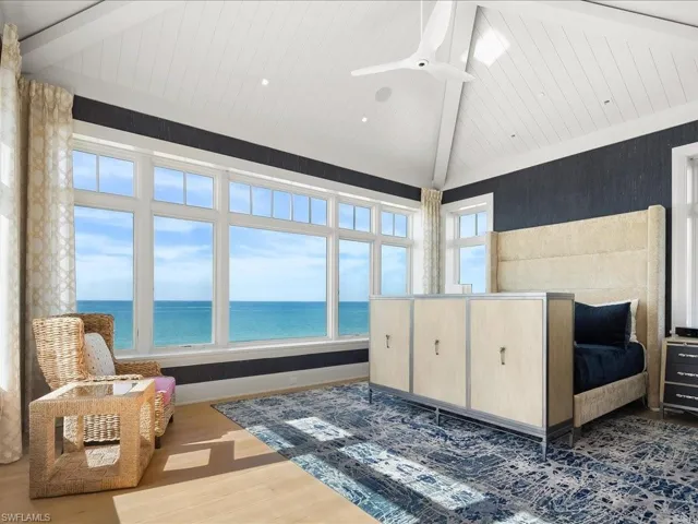 Bedroom featuring dark wood-style floors, a water view, high vaulted ceiling, and a ceiling fan