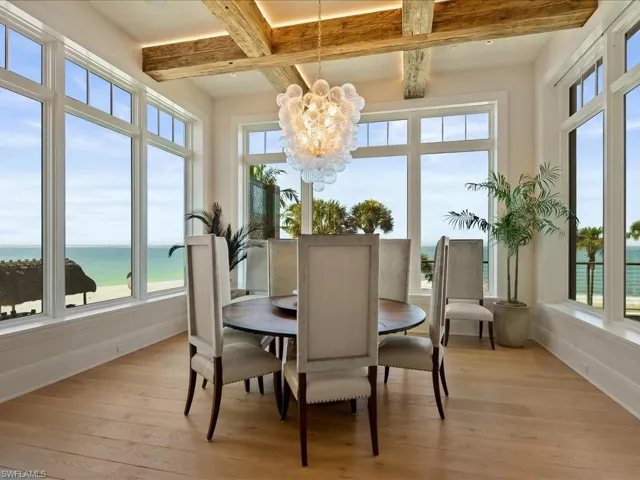 Dining room featuring a water view, light wood-type flooring, beam ceiling, and a chandelier