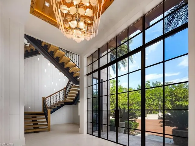 Entryway with a wall of windows, stairs, a chandelier, and a high ceiling