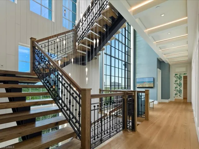 Stairs featuring plenty of natural light, a high ceiling, and wood finished floors