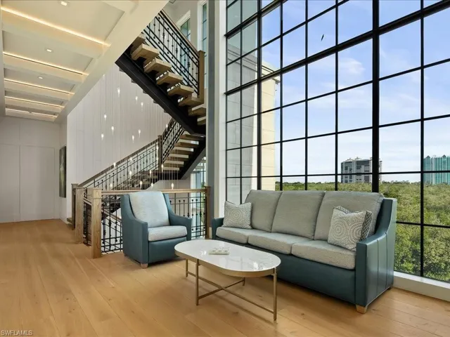 Living room with a city view, light wood-type flooring, and a towering ceiling