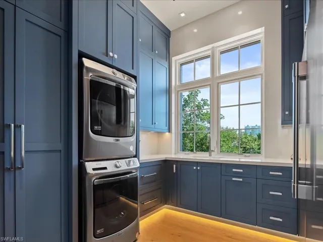 Laundry room featuring cabinet space, stacked washer and clothes dryer, and light wood-style flooring