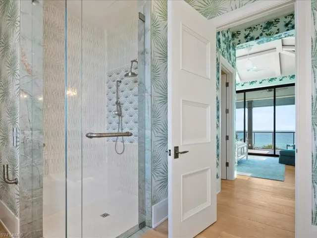 Full bathroom with a shower stall, wood finished floors, a ceiling fan, and wallpapered walls
