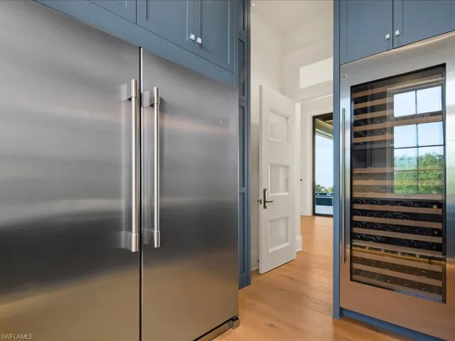 Kitchen featuring beverage cooler, built in fridge, blue cabinets, and light wood-style flooring