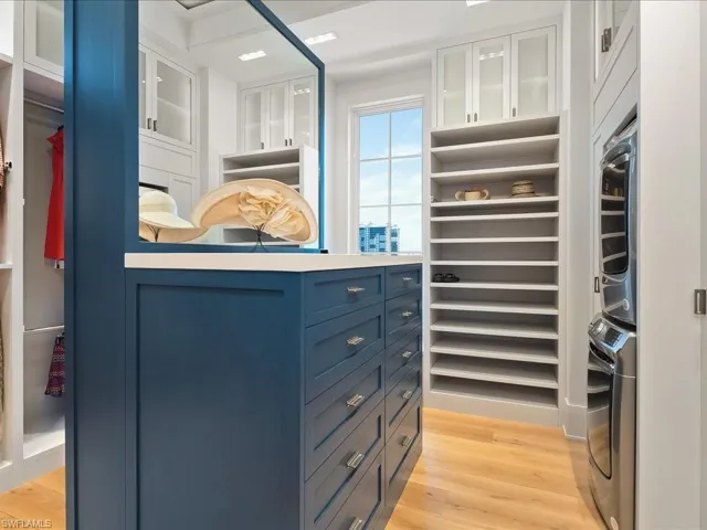 Walk in closet featuring light wood-style flooring and stacked washer / drying machine