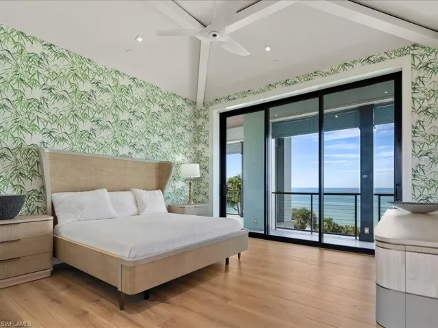Bedroom with wallpapered walls, a water view, access to exterior, light wood-style floors, and ceiling fan