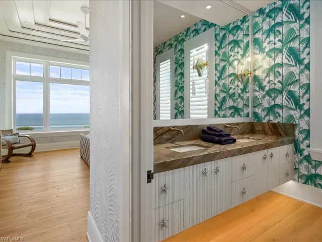 Bathroom with double vanity, wood-type flooring, wallpapered walls, a water view, and healthy amount of natural light