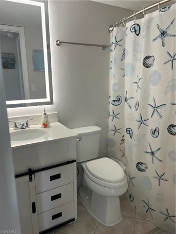 Bathroom featuring light tile patterned floors, a shower with curtain, and vanity