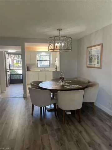 Dining space featuring dark wood-style flooring, a textured ceiling, and a chandelier