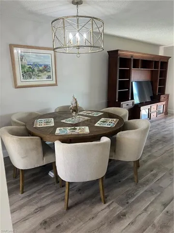 Dining area with a textured ceiling, light wood-type flooring, and a chandelier