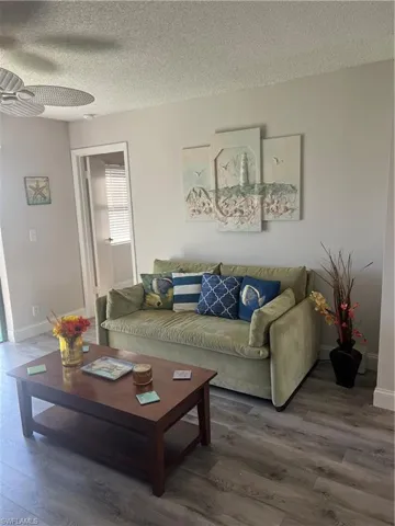 Living area with wood finished floors, a textured ceiling, and ceiling fan