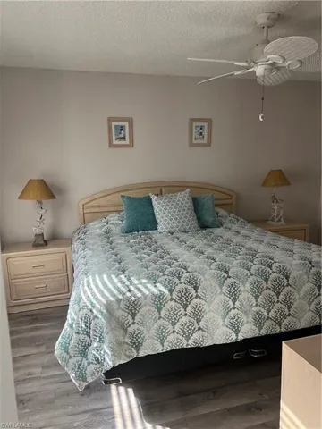 Bedroom with wood finished floors, a textured ceiling, and ceiling fan