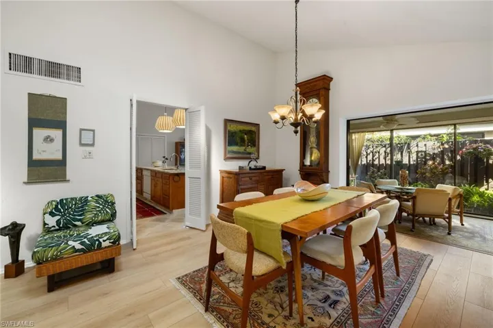 Dining area with high vaulted ceiling, visible vents, a notable chandelier, and light wood finished floors