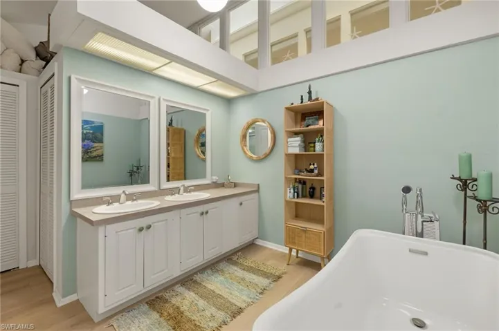 Full bath with a closet, a freestanding tub, a sink, and wood finished floors