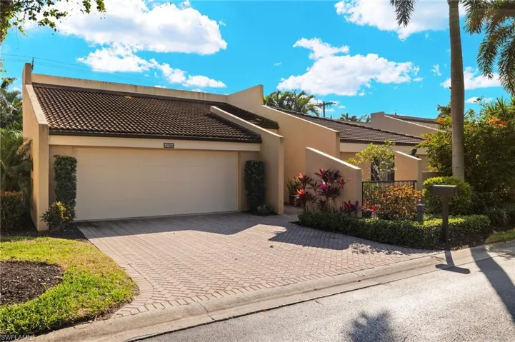 View of front of home with decorative driveway, a tile roof, an attached garage, and stucco siding