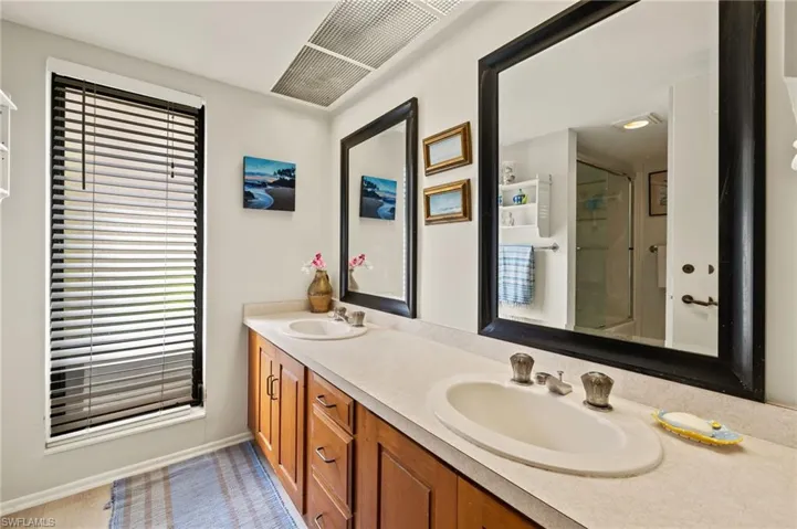 Bathroom featuring double vanity, a shower with door, and a sink
