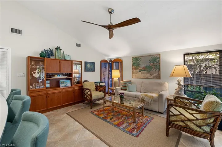 Living room with light tile patterned floors, ceiling fan, visible vents, and arched walkways