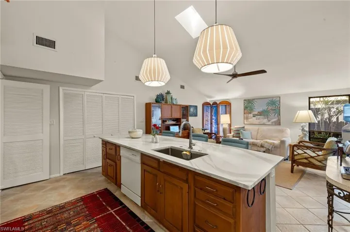 Kitchen featuring dishwasher, open floor plan, hanging light fixtures, a kitchen island with sink, and a sink