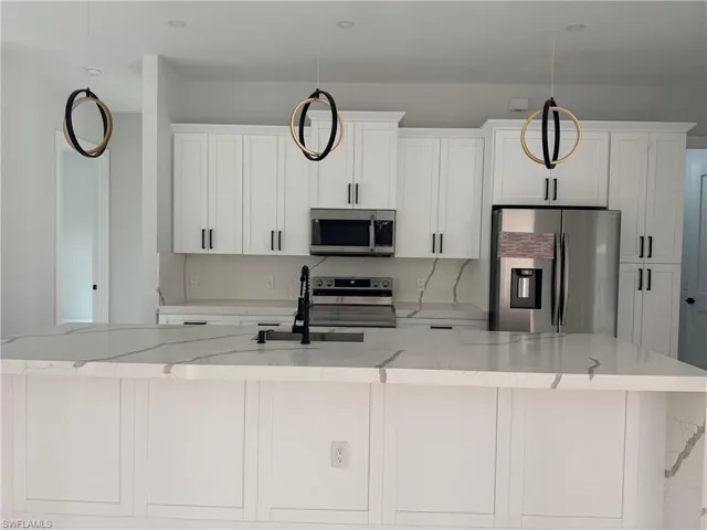 Kitchen with light stone countertops, an island with sink, and stainless steel appliances