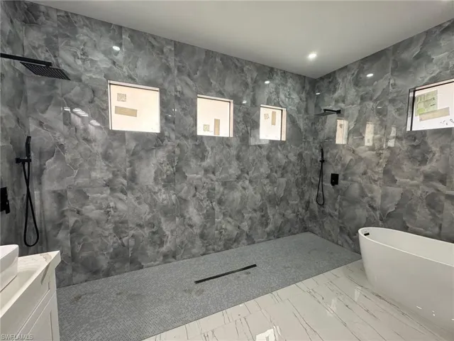 Bathroom featuring vanity, tile walls, and shower with separate bathtub