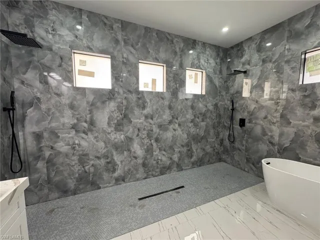 Bathroom featuring plus walk in shower, vanity, and a wealth of natural light