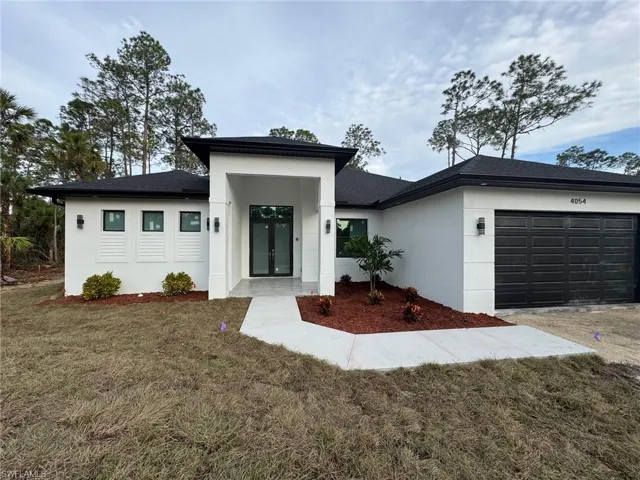 View of front of house featuring french doors, a front lawn, and a garage