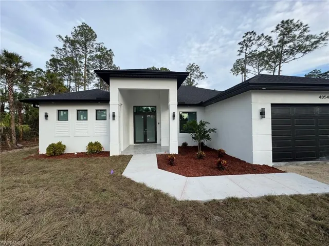 View of front of property featuring french doors, a front yard, and a garage
