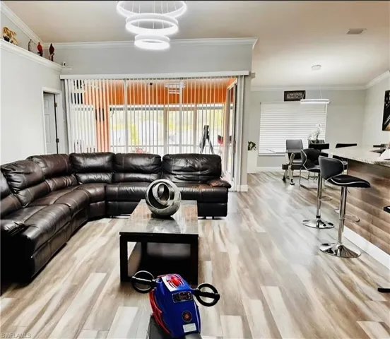 Living room with ornamental molding and light wood-style floors