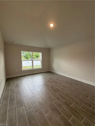 Unfurnished room featuring recessed lighting, vaulted ceiling, and wood finish floors