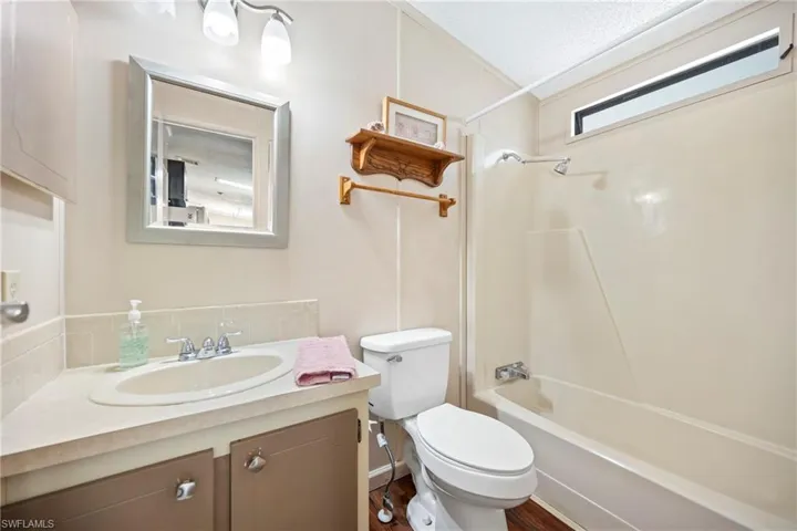 Bathroom with shower / bathtub combination, vanity, and dark wood-style floors