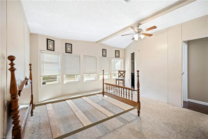 Bedroom with a textured ceiling, multiple windows, carpet flooring, and a ceiling fan