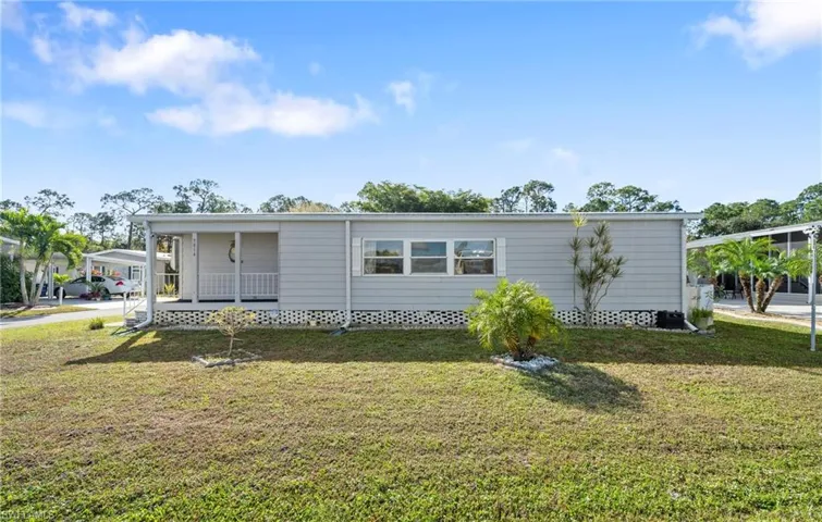 View of front facade with covered porch, a front lawn, and a carport