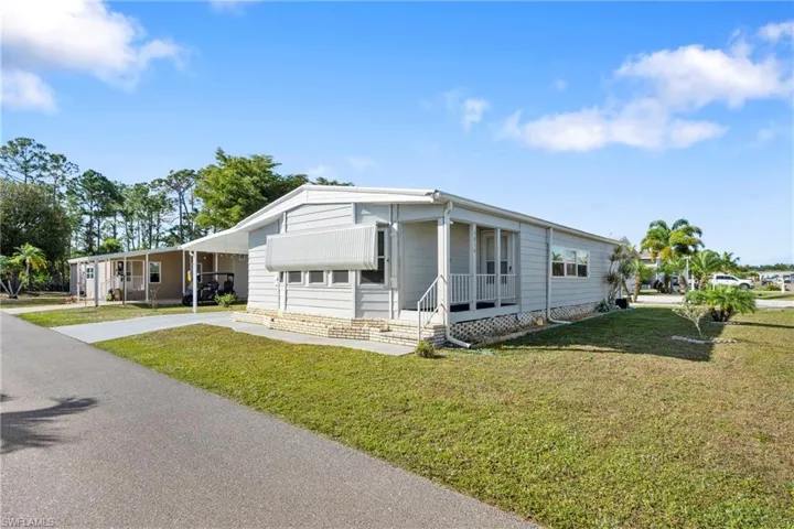 Manufactured / mobile home with a front yard, a porch, and driveway