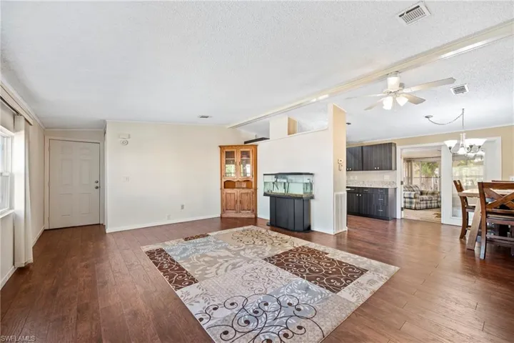 Living room featuring vaulted ceiling, a chandelier, dark wood-style floors, a textured ceiling, and a ceiling fan