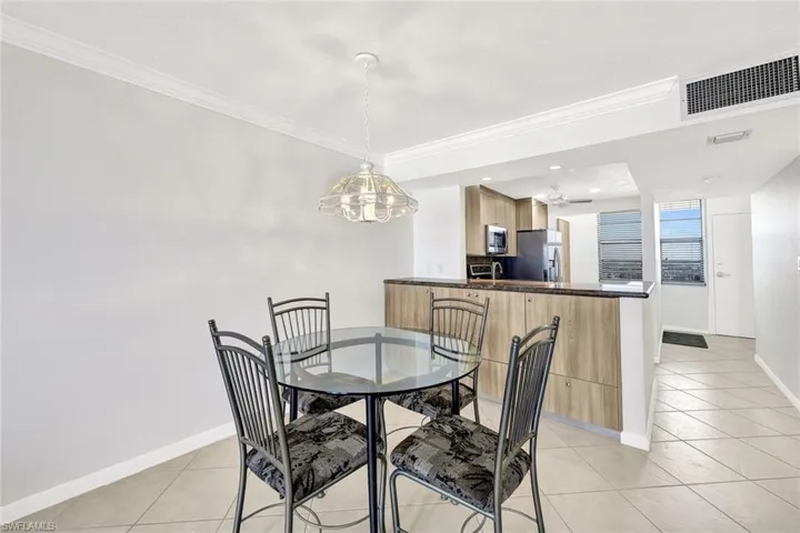 Dining room with light tile patterned floors, crown molding, recessed lighting, and a chandelier
