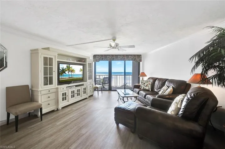Living area with crown molding, a textured ceiling, light wood-type flooring, and ceiling fan