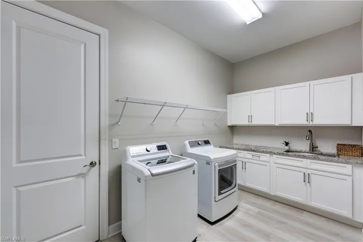 Laundry room with cabinets, light hardwood / wood-style flooring, sink, and independent washer and dryer