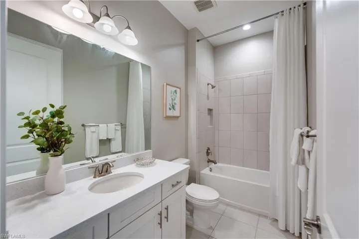 Full bathroom with shower / tub combo with curtain, vanity, toilet, and tile patterned floors