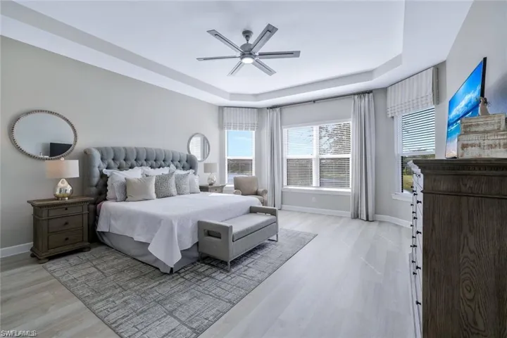 Bedroom featuring light wood-type flooring, ceiling fan, and a raised ceiling