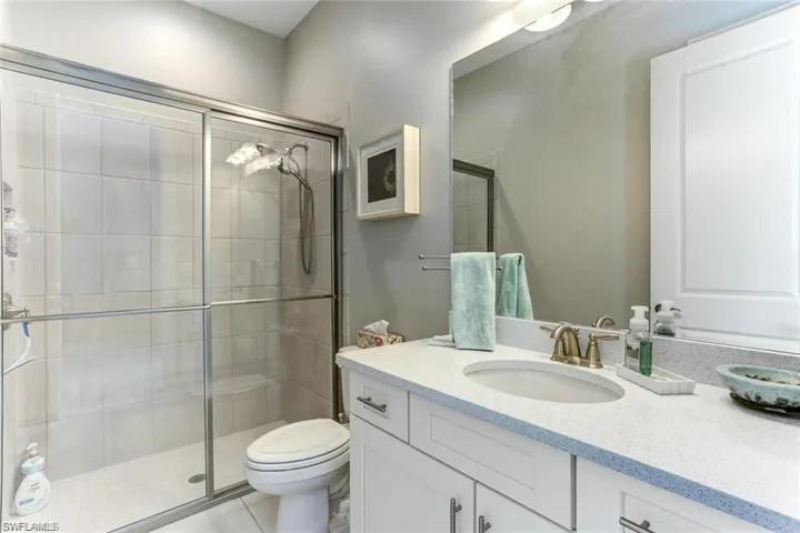 Bathroom with walk in shower, tile patterned flooring, vanity, and toilet
