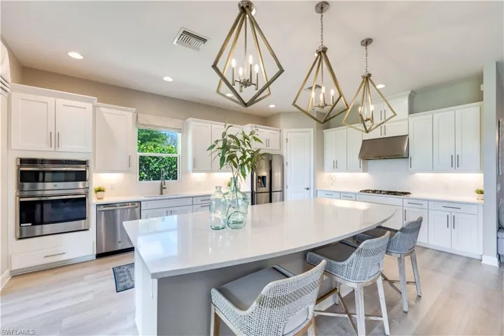Kitchen featuring appliances with stainless steel finishes, white cabinets, a chandelier, and decorative light fixtures