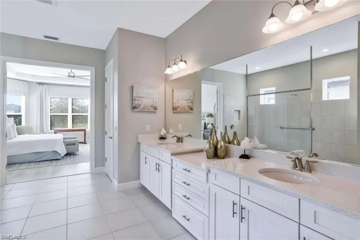 Bathroom with tile patterned flooring, ceiling fan, vanity, and tiled shower