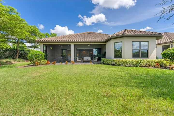 Back of property with ceiling fan and a yard