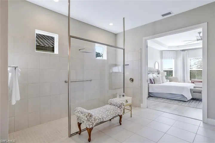 Bathroom featuring ceiling fan, a healthy amount of sunlight, and tiled shower