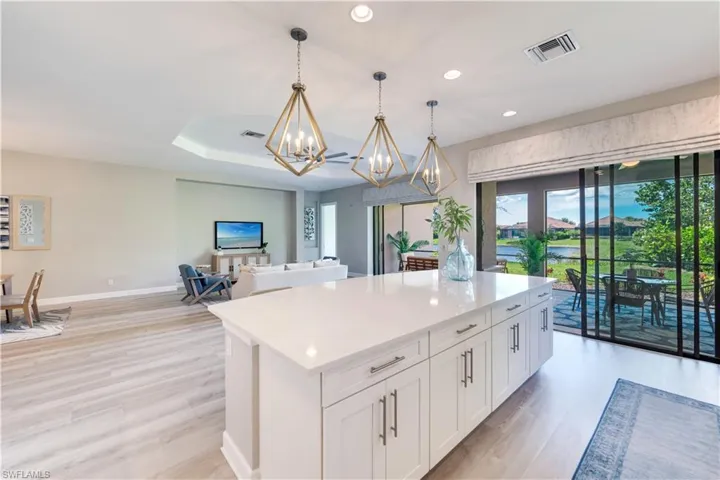 Kitchen with light hardwood / wood-style floors, white cabinetry, a kitchen island, pendant lighting, and a notable chandelier
