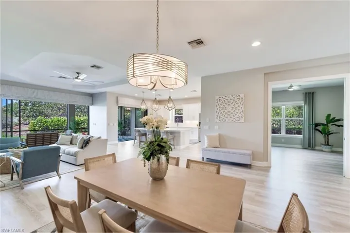 Dining room featuring ceiling fan with notable chandelier, light hardwood / wood-style floors, and a tray ceiling