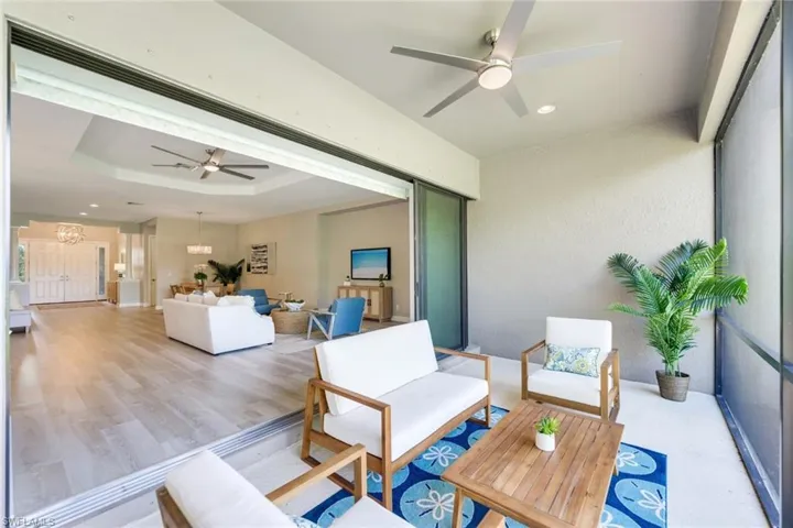 Living room featuring light wood-type flooring, ceiling fan, and a raised ceiling
